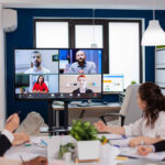 Et møterom der noen sitter og har et videomøte med mange ande.